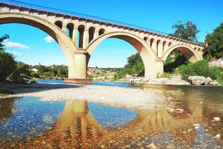 Reflection of the Collias stone bridge on the Gard river in Occitanie Franceの写真素材