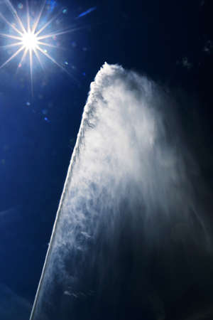 Powerful jet of water lit by the sun against the light.