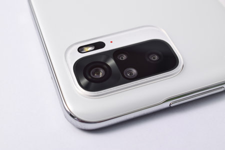 Smartphone quad camera module. New modern white smartphone with quad camera module isolated on white background. Closeup of smartphone camera lensの写真素材