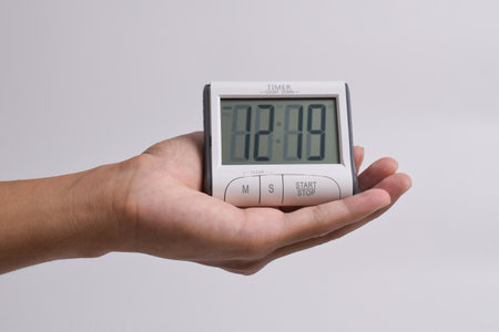 Man's hand holding a Digital kitchen timer on white background. count down clock for cooking