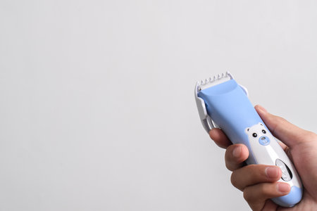 Hand holding Wireless hair trimmer for babies and children isolated on a white background.の写真素材