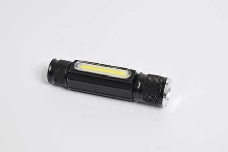 Modern metal LED flashlight in black color isolated on white background. Portable flashlight, LED camping flashlightの写真素材