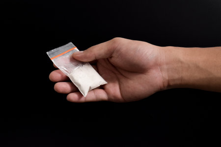 Hand giving cocaine in plastic package isolated on black background. Illustration of illegal drug...