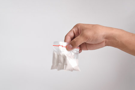 Hand giving cocaine in plastic package isolated on white background. Illustration of illegal drug substances, narcoticsの写真素材