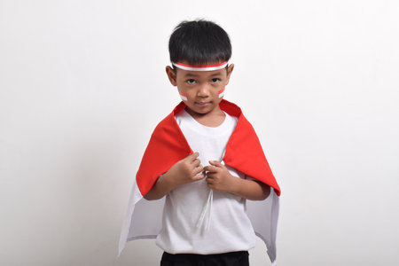 Cute little Asian boy wearing indonesian flag headband and robe. Concept of Indonesia's independence day on August 17の写真素材