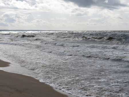 Stormy Baltic sea. Sun shining from behind clouds make it look like silver metalの写真素材
