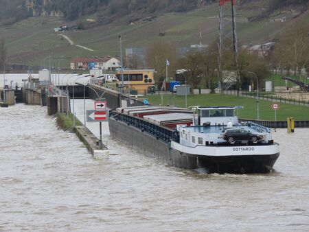 Grevenmacher, Luxembourg March 16, 2019. River cargo boat entering lock on Moselle river on a spring day with high waterのeditorial素材