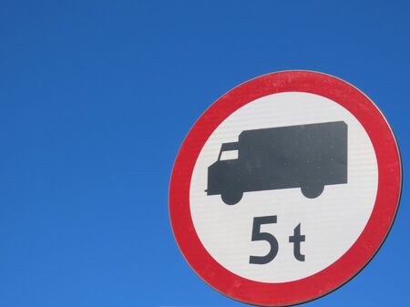 Road sign No trucks 5 t white and red on blue sky background. Europe