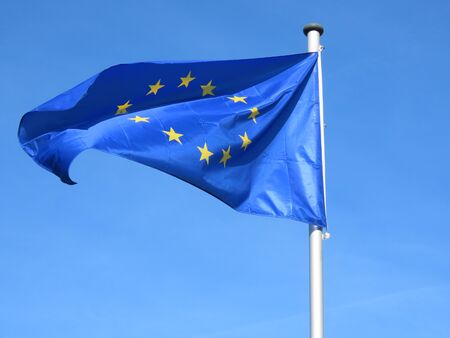 European Union EU flag bold and proud floating in the wind, against sunny blue skyの写真素材