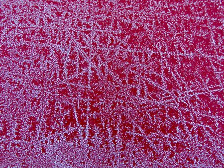 Ice crystals forming frost flower patterns on a red surface in cold winter, as background textureの写真素材