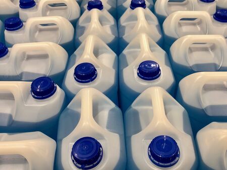 Rows of white plastic bottles with blue plastic caps, containing blue windscreen wiper liquidの写真素材