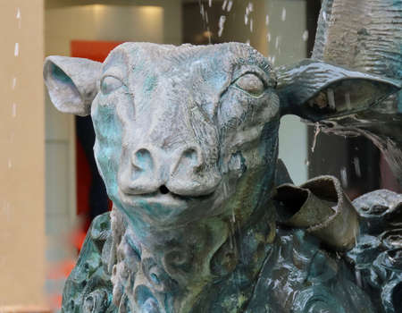 Luxembourg, Luxembourg - August 8, 2019. Close up of a sheep face from green copper sculpture with dancing musicians and happy sheep - modern fountain Roude Petz in old town, famous meeting pointのeditorial素材