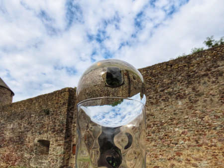 Medieval castle ruin in Pettingen, Luxembourg seen through crystal ball. The cut glass holder further distorts the image inside the ballの写真素材