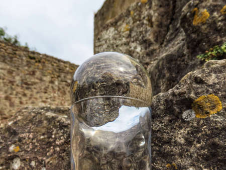 Medieval castle ruin in Pettingen, Luxembourg seen through crystal ball. The cut glass holder further distorts the image inside the ballの写真素材