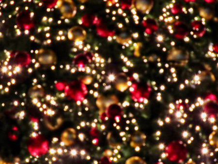 Defocused bokeh Christmas tree themed background with red and gold baubles, tree branches, small LED lights at nightの写真素材