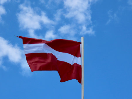 Latvian flag waving in strong wind on a sunny summer dayの写真素材