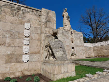 Military Cemetery in Riga. 1 of 4 Latvian warrior with shield sculptures and further - central sculpture Mother Latvia. Sunny spring day in Riga, Latvia - May 1, 2021のeditorial素材