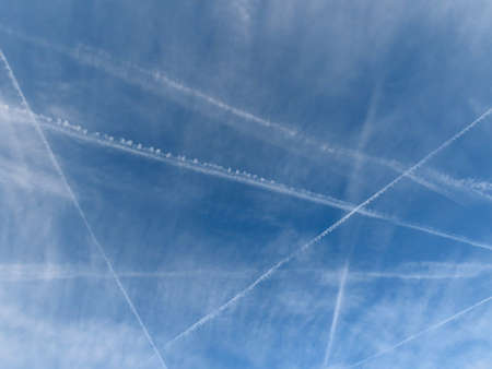 Blue sky with white condensation trails make bright crisscross pattern