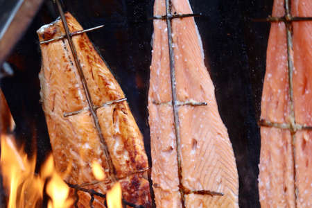 Flames of fire roasting filet pieces of salmon in the background. Christmas market in Luxembourg