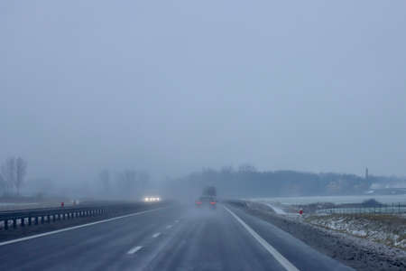 Dangerous driving conditions on motorway with fog, snow, sleeth, black ice, light rain, low...
