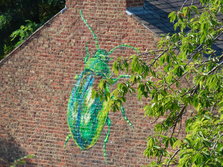 Green rose chafer artwork on typical red brick wall in York, England, UK - September 9, 2021