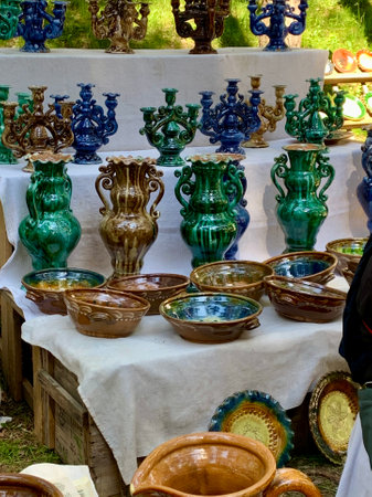 Merchandise on annual biggest crafts market in Latvian Ethnographic Open Air museum. Bright green and brown traditional glazed ceramic vases, dishes, and candle holders. Riga, Latvia - June 4, 2022のeditorial素材