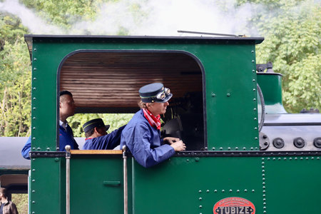 Engineer looking out of steam locomotive Tubize driving on railway tracks, side view. Fond-de-Gras,...