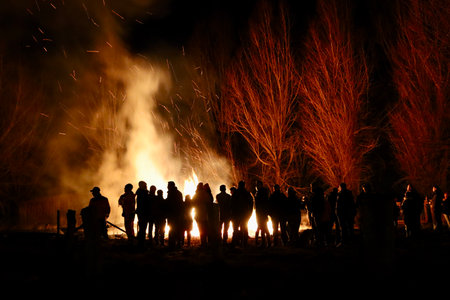 Buergbrennen festival in Luxembourg. Celebrating end of winter beginning of spring by burning mock castles. Black silhouettes of people admiring fire. Walferdange, Luxembourg - February 26, 2023のeditorial素材