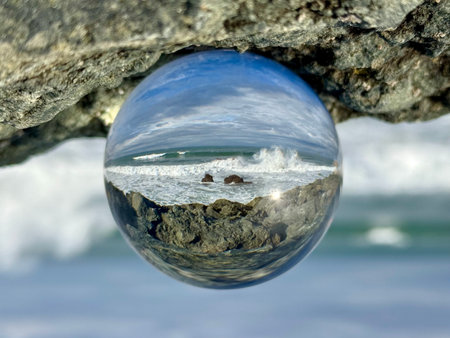 Lensball reflecting a seascape Bay of Biscay at Biarritz, Milady beach. Waves splashing over rocks