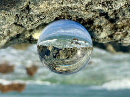 A crystal ball reflecting a seascape of the Bay of Biscay at Biarritz, Milady beach. Waves splashing over rocksの写真素材