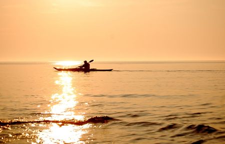 A lone kayaker braves the emptiness of Lake Michigan and a path of liquid gold. Near Jacksonport, Wis., at sunrise.の写真素材
