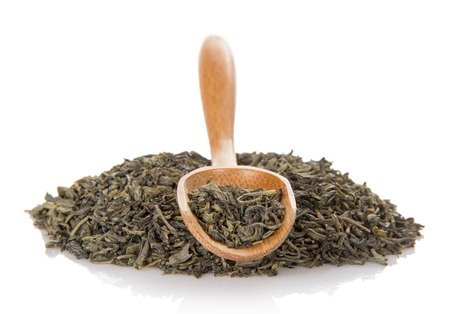 Dry green tea in the wooden spoon, isolated on whiteの写真素材