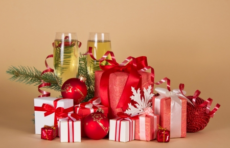 Gift boxes, Christmas toys, serpentine and wine glasses with champagne on a beige backgroundの写真素材