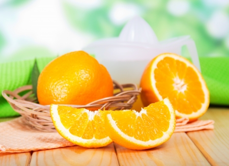 Segments of orange and a juice extractor against green foliageの写真素材