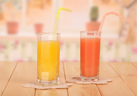 Two glasses with orange and grapefruit juice against kitchenの写真素材