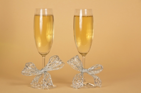 Two glasses with the champagne, decorated silver ribbons on a beige backgroundの写真素材