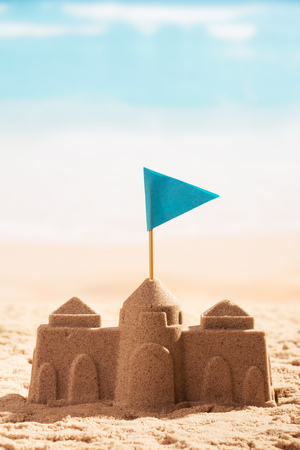 Castle in the sand and flag close-up on a background of the sea.の写真素材
