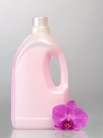 Pink plastic bottle with liquid detergent and orchid flower on a gray background.の写真素材