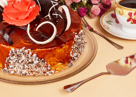 Chocolate cream cake, fork, scapula and cup of tea on a beige background.の写真素材