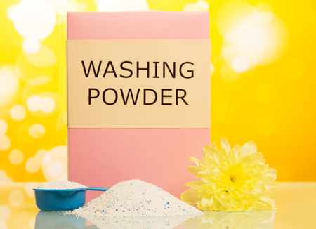 The pack of washing powder in a measuring cup on abstract yellow background.の写真素材