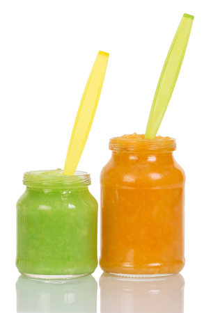 Opened jars baby vegetable puree with a plastic spoon isolated on white background.の写真素材