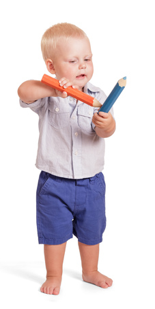Charming boy in a shirt and shorts standing and holding two large pencil isolated on white background.の写真素材