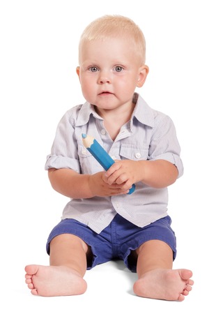 Charming baby sitting and holding a big pencil isolated on white background.の写真素材