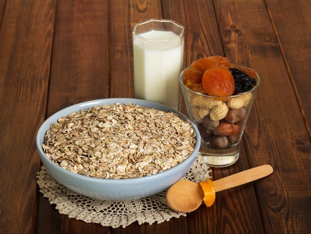 A bowl of oatmeal, a glass of milk and a spoon on a background of dark wood.の写真素材