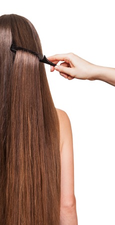 A barber's hand combing her long straight hair isolated on white background.の写真素材