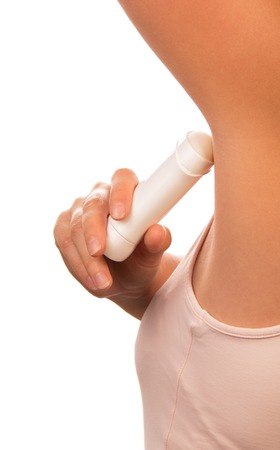 An unidentified woman uses a dry underarm deodorant isolated on white background.の写真素材