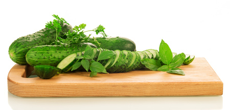 Whole cucumbers and kruzhochki, parsley, basil, wooden board isolated on white background.の写真素材