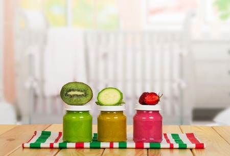 Glass jars with vegetable and fruit puree, kitchen towel on the background of the kitchen.の写真素材