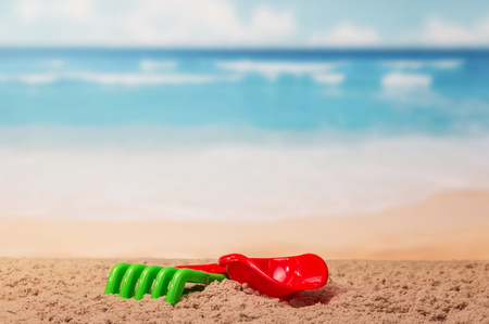 Children's toys shovel and rake in the sand on the sea background.の写真素材