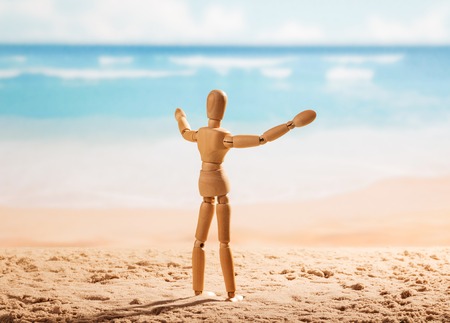 Wooden doll with open arms is worth on the seashore.の写真素材